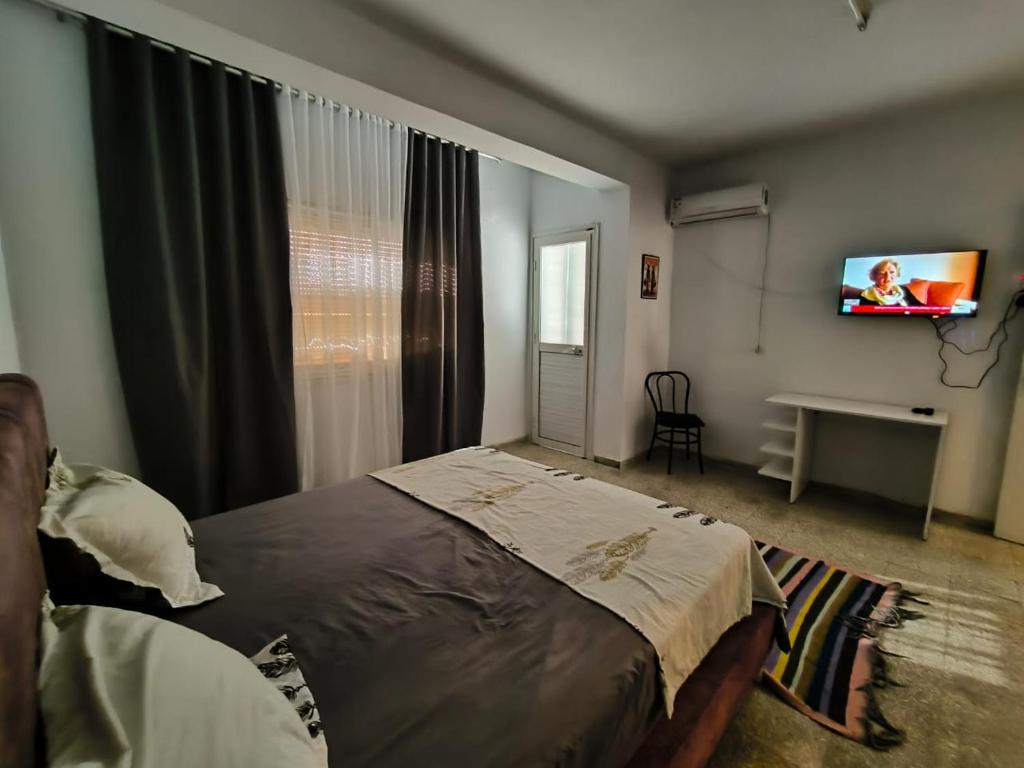 1 dormitorio con 1 cama y TV en la pared en Spacious 3 room apartment Prime Location on 2nd Floor with proximity to all amenities en Sfax