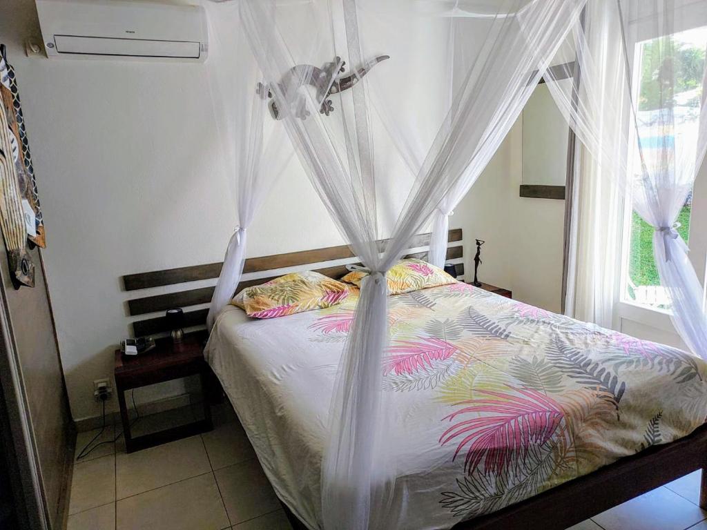 - une chambre avec un lit avec des rideaux et une fenêtre dans l'établissement Chamb'Bouchons, à Saint-François