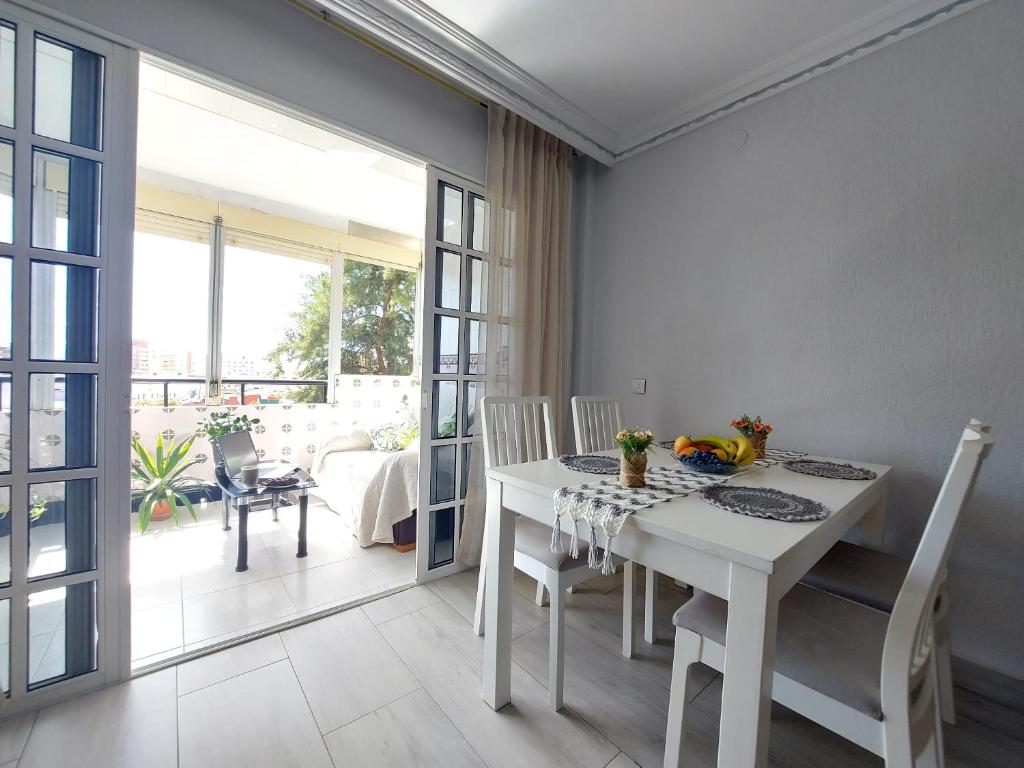 una sala da pranzo bianca con tavolo e sedie bianchi di Habitación Privada a 15 min de la Playa/Piso a Huelva