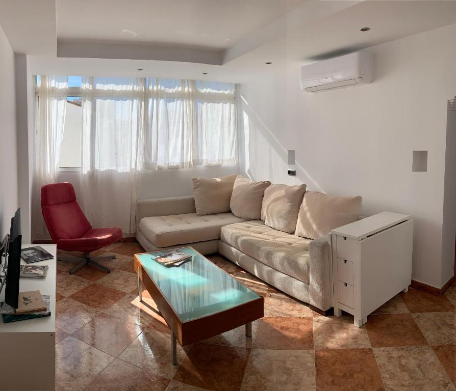 sala de estar con sofá y silla roja en Los Guindos, en Málaga