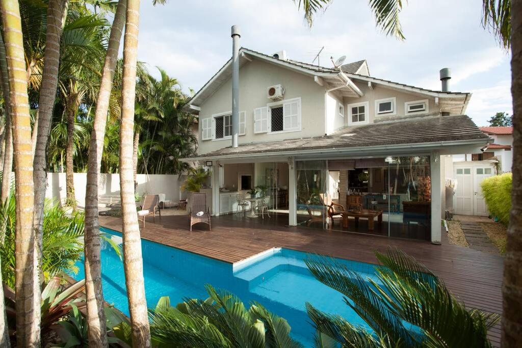 uma casa com piscina em frente a uma casa em Praia Mole, Florianopolis, paraiso. em Florianópolis