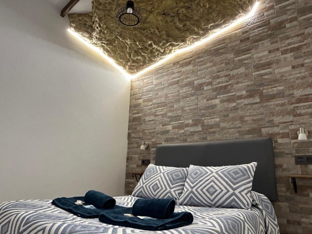 um quarto com uma cama e uma parede de tijolos em Casa entre Rocas Setenil em Setenil