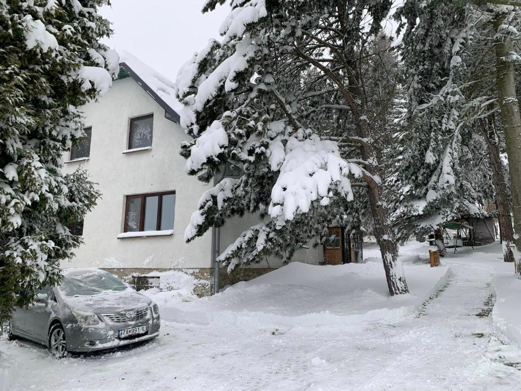 un coche aparcado frente a una casa cubierta de nieve en Chata na lúke, en Tatranská Štrba