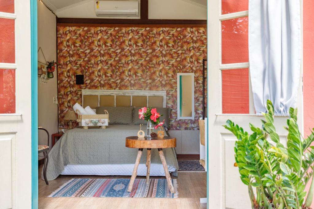 Un dormitorio con una cama y una mesa con flores. en Paradise Bangalô en Florianópolis