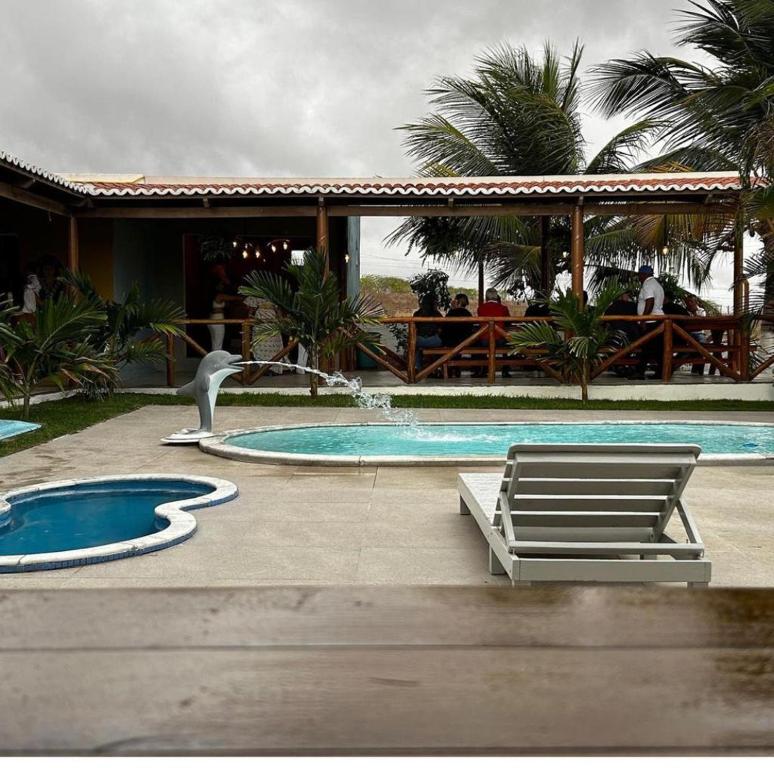 a pool with a swan and two chairs and a bird at Pousada Aconchego Brisas e Ventos in Olho D’Água do Casado