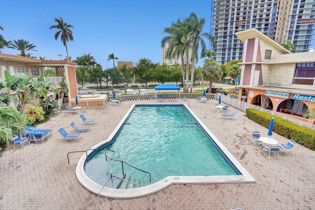 uma piscina vazia com cadeiras e um edifício em Walk to Hallandale Beach Pool Christmas Retreat em Hallandale Beach