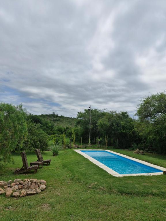 einen Pool in einem Garten mit zwei Stühlen in der Unterkunft El Rincon de Jose Luis - Cabañas y Restaurante in Tanti
