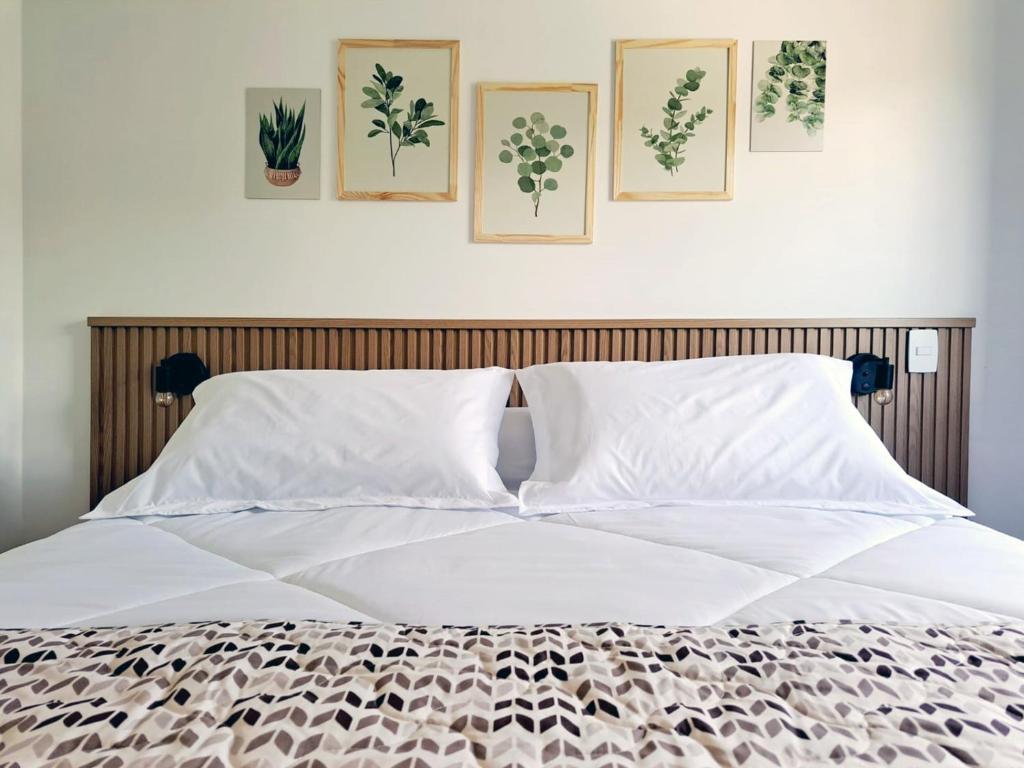 a bedroom with a white bed with four pictures on the wall at Casa dos Lírios in Alto Paraíso de Goiás