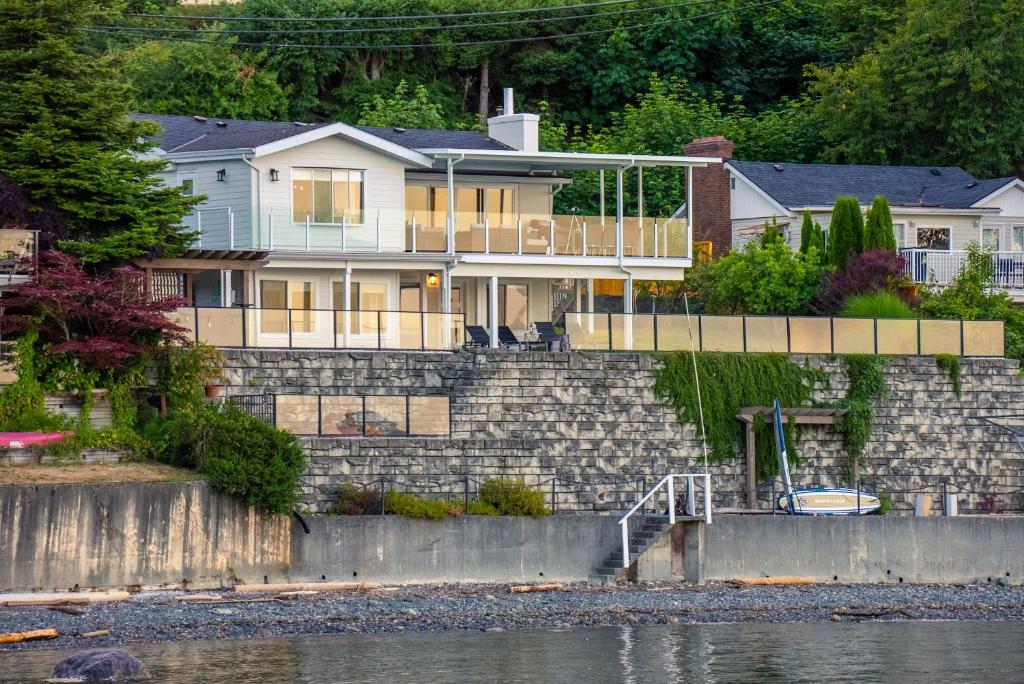 a house on a stone wall next to the water at Oceanfront Villa in Ladysmith