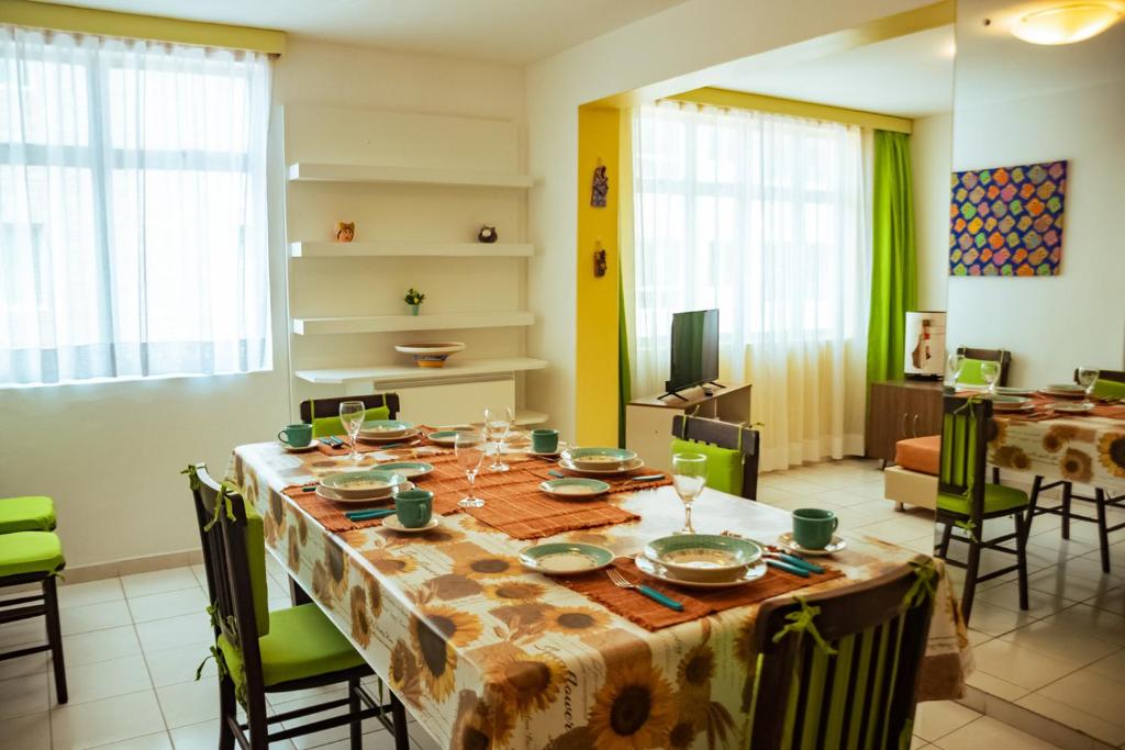 a dining room with a table with plates and glasses at Apto a 350m da Praia de Ponta Verde, em Maceio AL in Maceió