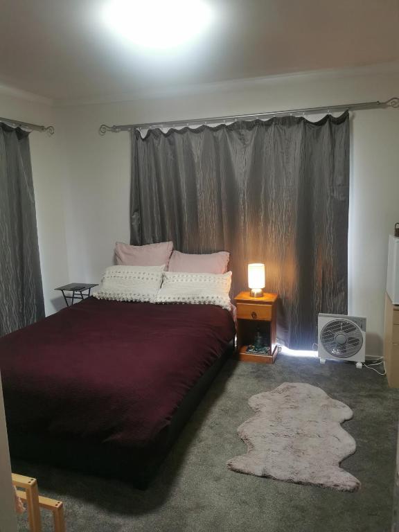 a bedroom with a bed and a table with a lamp at Cozy Double Room - WIFI in Hamilton