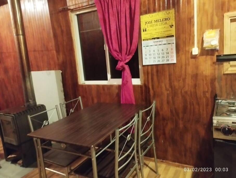 a kitchen with a table and a window with a red curtain at Cabañas Don Esteban in Tortel