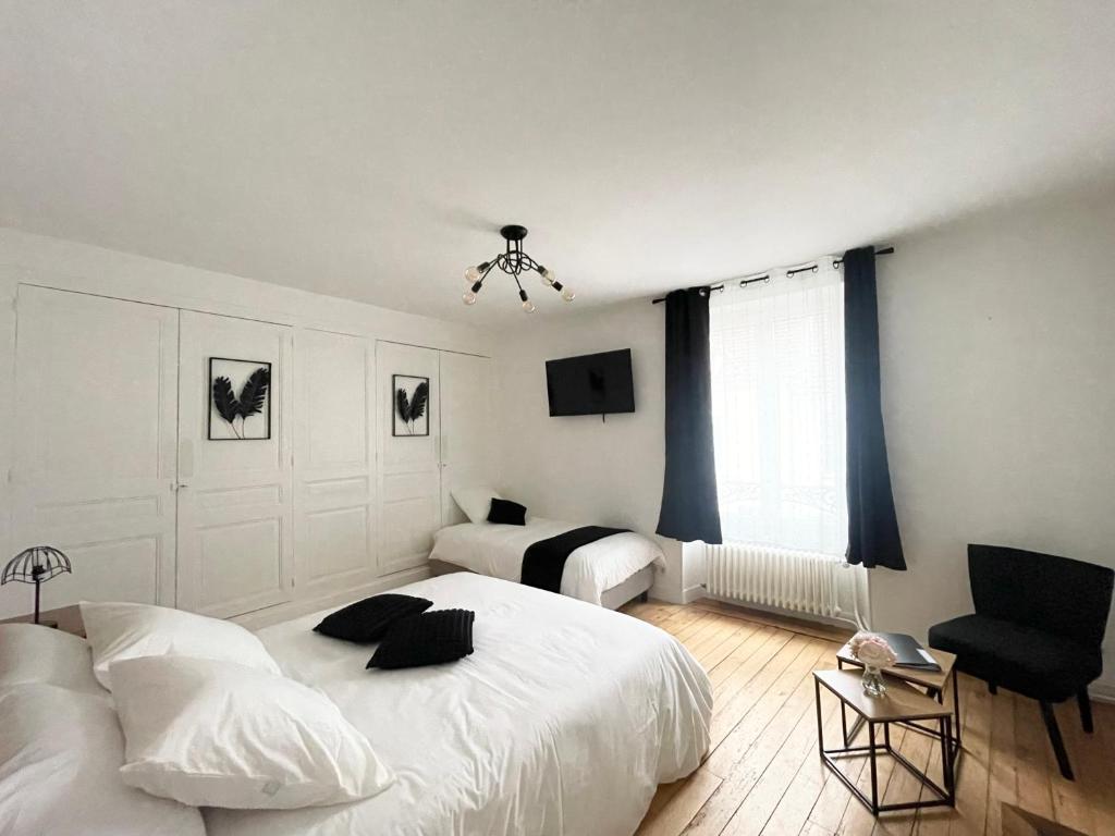 a white bedroom with two beds and a window at La Demeure des Hôtes 10 minutes de Disney in Couilly-Pont-aux-Dames