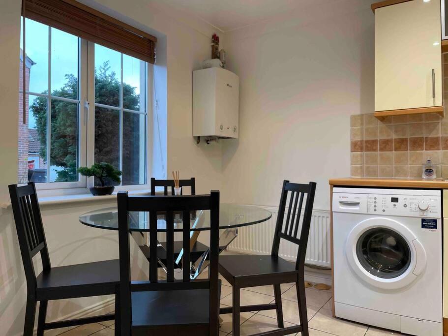 a kitchen with a table and chairs and a washing machine at Chineham Retreat - Spacious Home For Leisure & Business Stays - Sleeps 8 in Sherborne Saint John