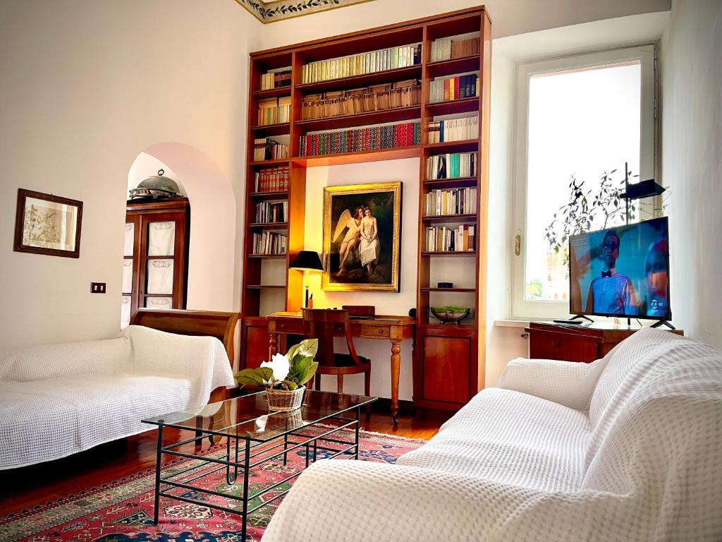 una sala de estar con 2 sofás blancos y un estante para libros. en Colosseum Luxury Apartment, en Roma