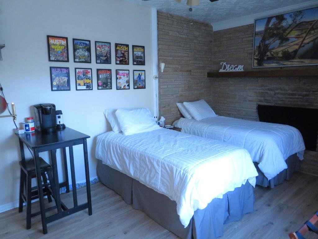 a bedroom with two beds and a desk with a television at Studio SoCo in Austin