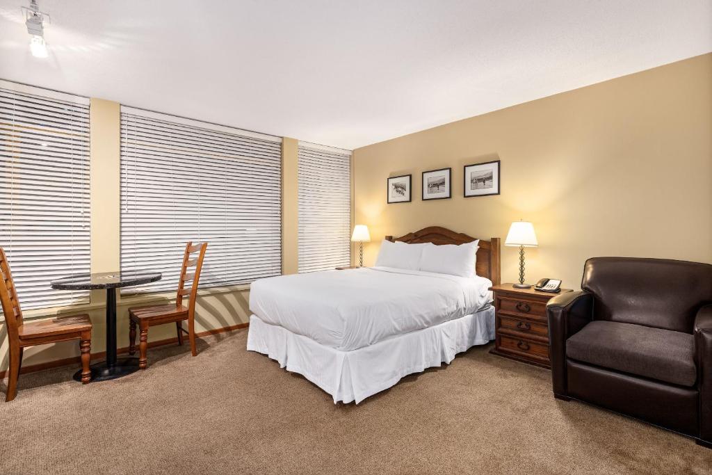 a bedroom with a bed and a chair and a table at Cascade Lodge suite GENIUS SPECIAL WIFI cable HDTV across from Whistler Village air conditioning heating pay underground parking pool 2 hot tubs sauna gym in Whistler