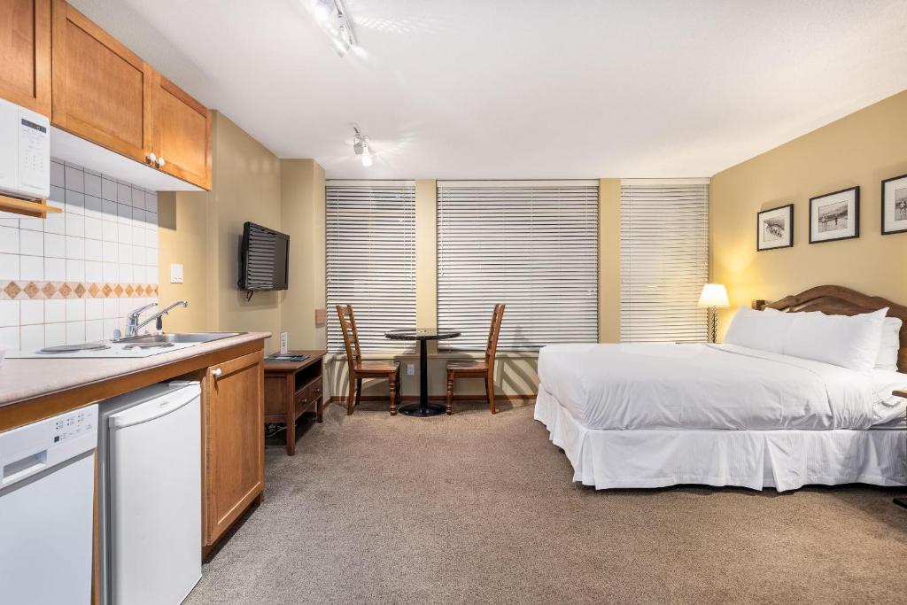 een slaapkamer met een bed en een keuken met een tafel bij Cascade Lodge suite WIFI cable HDTV pool hot tubs sauna gym in Whistler