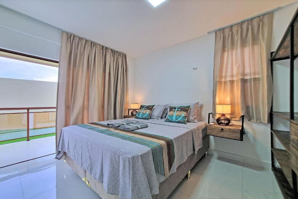 een slaapkamer met een bed en een groot raam bij Condomínio Villamar em Paracuru por Carpediem in Paracuru