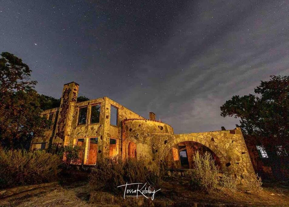 una vecchia casa in pietra, seduta in cima a un campo. di Bunkhouse at the Silver Spur Dancehall Ruins~Bandera, TX. a Bandera