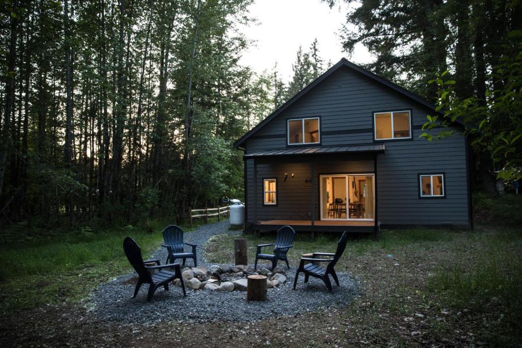una pequeña casa negra con sillas delante en Evergreen Cabin BY Betterstay, en Ashford