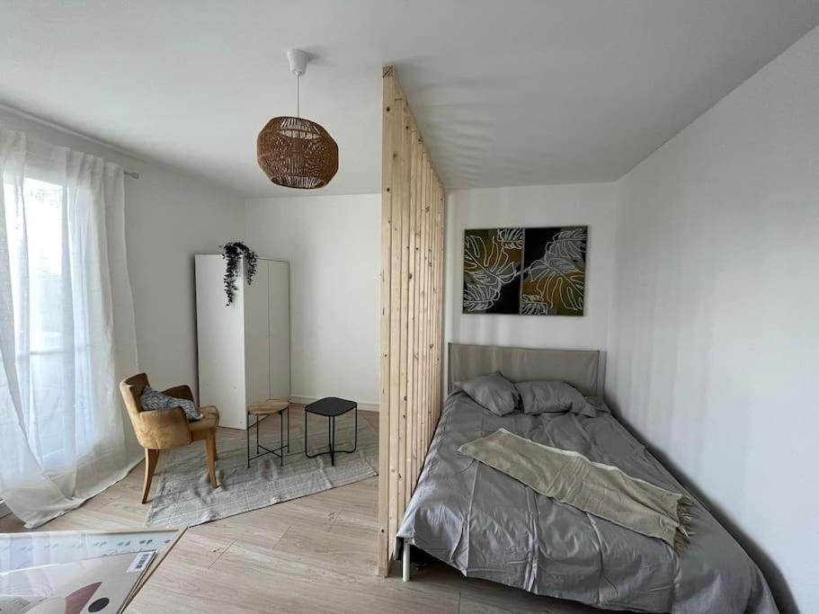 een slaapkamer met een bed, een tafel en een stoel bij Le chic appartement de Gagny/parking gratuit in Gagny