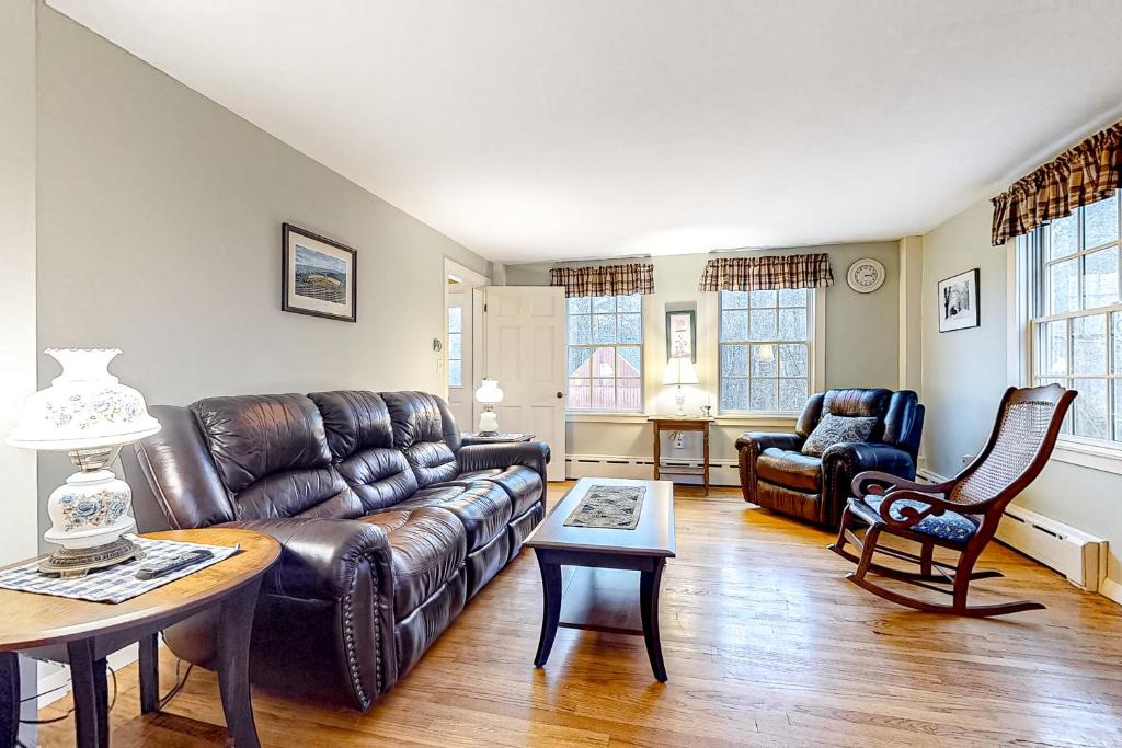 ein Wohnzimmer mit einem Ledersofa und einem Tisch in der Unterkunft Sugarwood Farmhouse in Wilmington