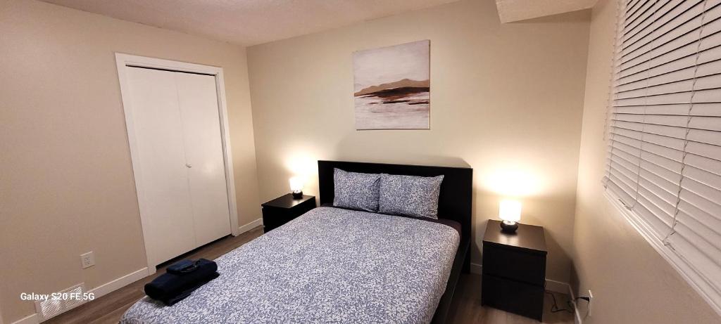 een kleine slaapkamer met een bed en 2 lampen bij Home away from home - 6 bedroom fantastic bungalow in Winnipeg