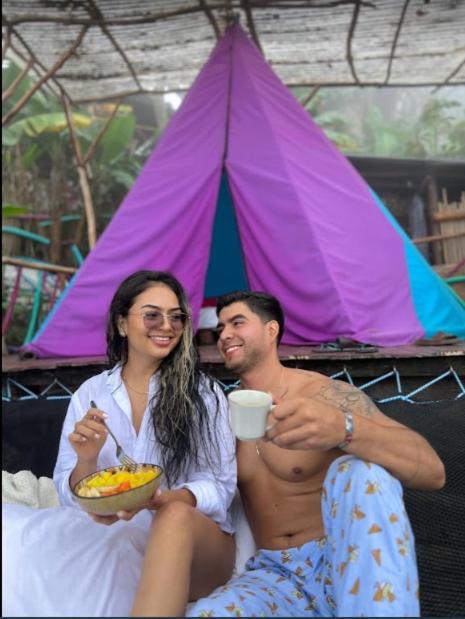 a man and a woman sitting on a bed eating food at Mano del Gigante Nomada in Gigante