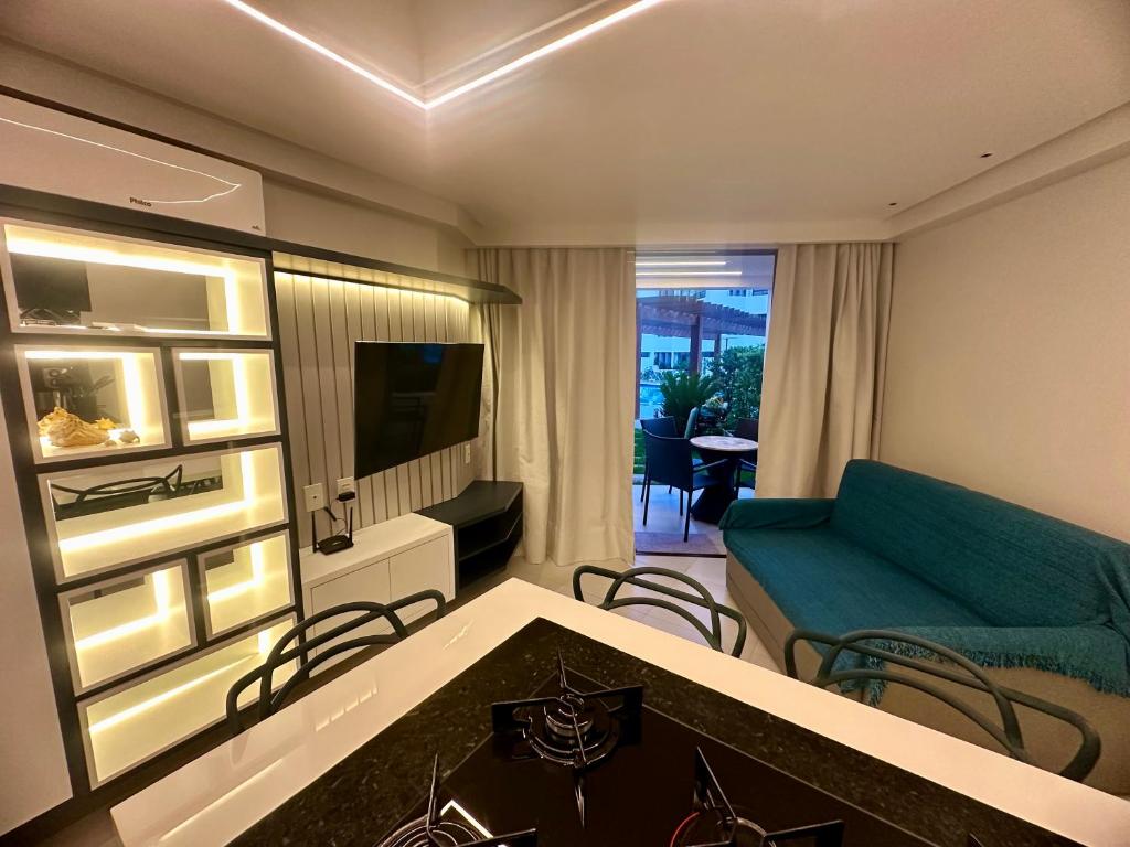 een woonkamer met een bank en een televisie bij Flat Luxo - Pé na Areia - Maui Beach Residence in Tamandaré
