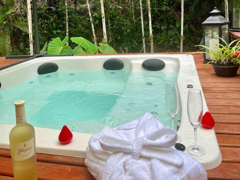 a hot tub with a bottle of wine and a glass at Jardins da Vila - Farm house in Blumenau