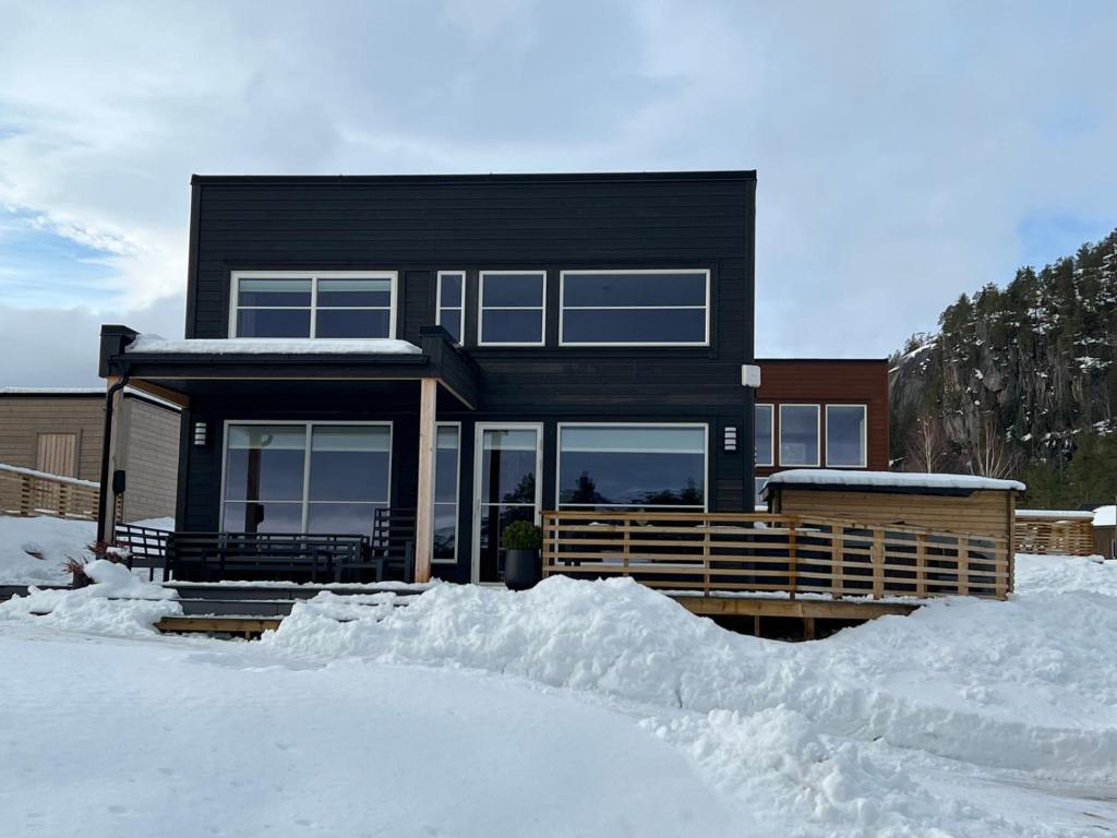 una casa negra con nieve delante en Modern lakehouse with sauna, near golf and alpine, en Vradal