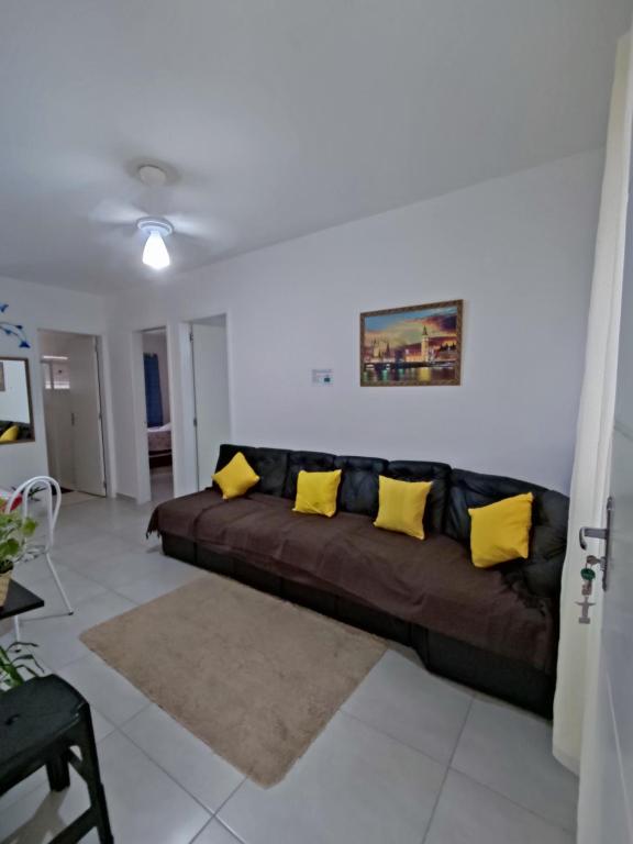 - un salon avec un canapé brun et des oreillers jaunes dans l'établissement Cond Cristal Indaiá I Ap23, WI-FI, 450m praia Indaiá, check-out 16h, à Bertioga