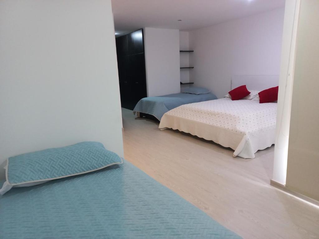 1 dormitorio con 2 camas y alfombra azul en Lujoso Hospedaje en las Alturas, en Tunja