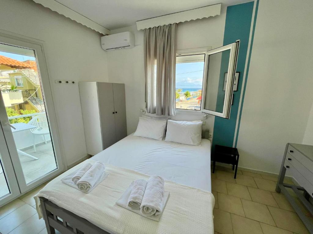 1 dormitorio con 2 camas y ventana grande en Afrodite II, en Sarti