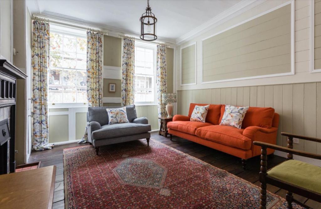a living room with an orange couch and a chair at 3 Bedroom in the Heart of West End in London