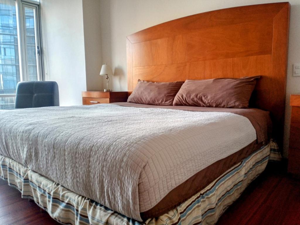 um quarto com uma cama grande e uma cabeceira em madeira em AMAZING REFORMA APARTMENT, 2 brms 2 bath, AWESOME em Cidade do México