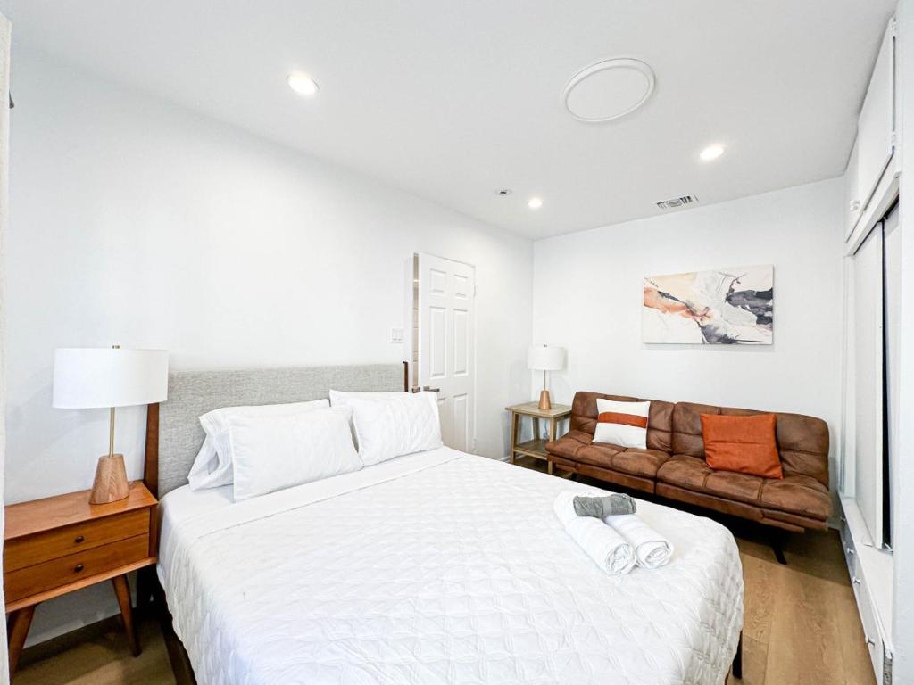 een witte slaapkamer met een bed en een bank bij Modern 2-Bedroom Gem Close to Beverly Hills - DOH2 in Los Angeles