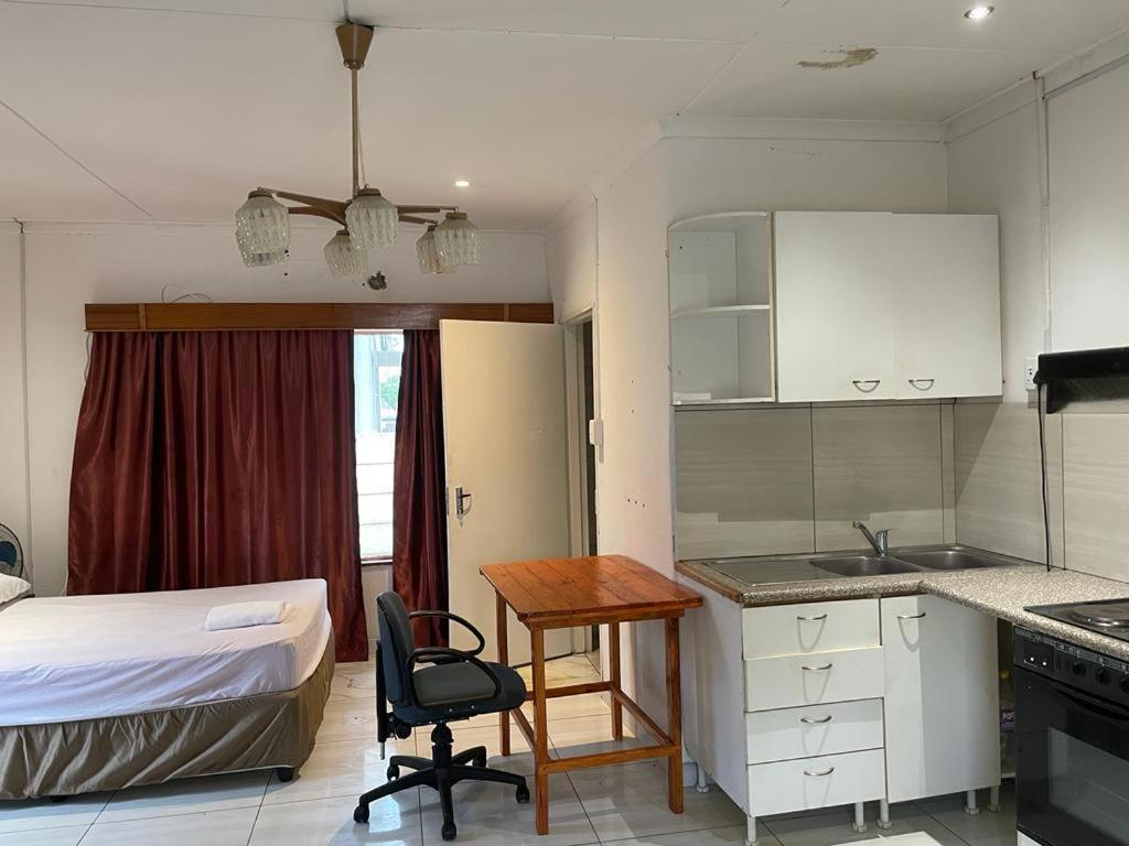 a bedroom with a bed and a kitchen with a desk at De la posh Travels and tours in Windhoek