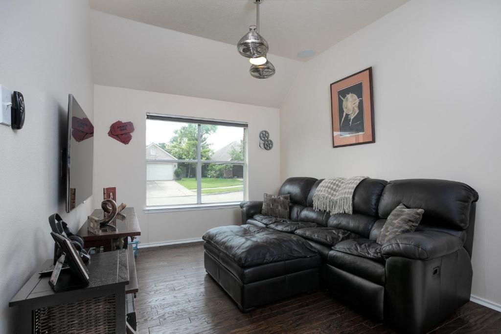 a living room with a leather couch and a window at Fully Furnished Ranch Style Home Close To Houston in Pearland