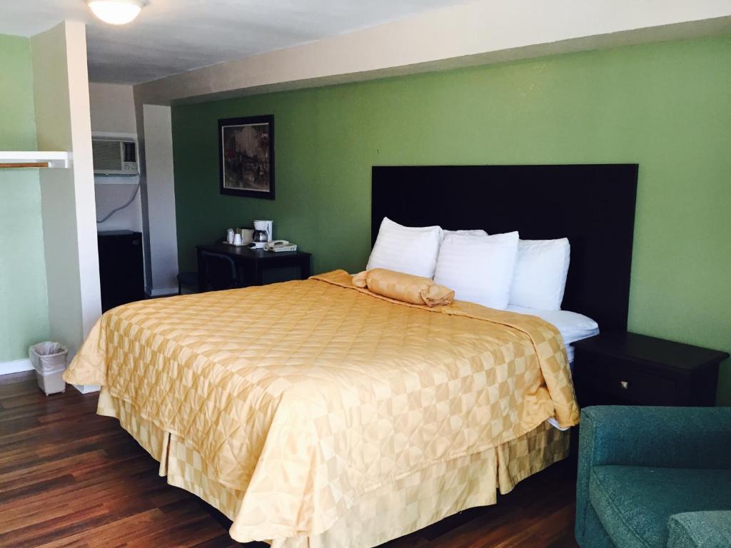 a bedroom with a bed and a green wall at Executive Inn & Kitchenette Suites-Eagle Pass in Eagle Pass