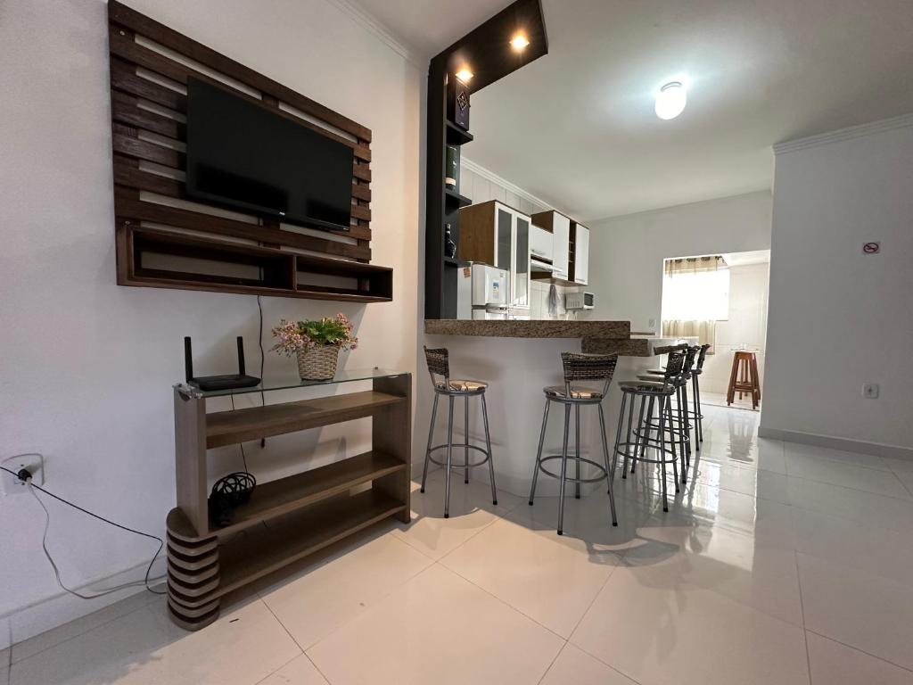 a living room with a tv and a bar with stools at Apartamento da Jana a 1,5km praia in Porto Seguro