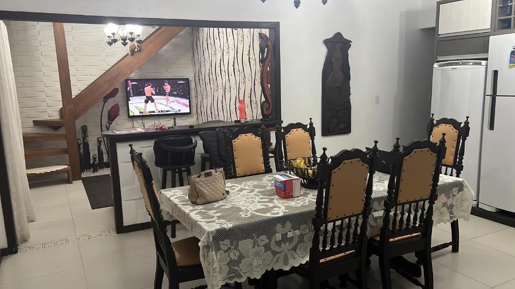 Un comedor con mesa y sillas y un televisor. en Hostel quartos privados Ouvidor, en Garopaba