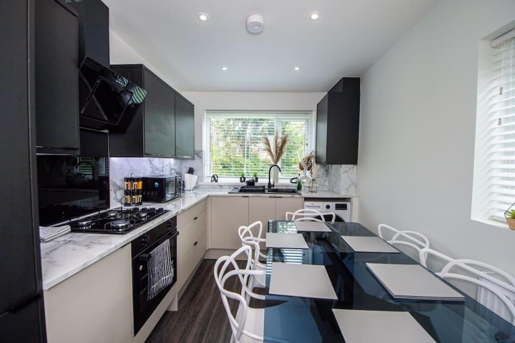 una cocina con armarios en blanco y negro, mesa y sillas en Modern 4-Bed Retreat with Garden en Mánchester