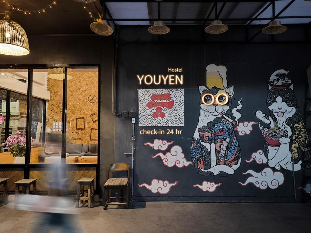 a person walking past a wall with a mural of a cat at Youyen Hostel in Ban Don Muang