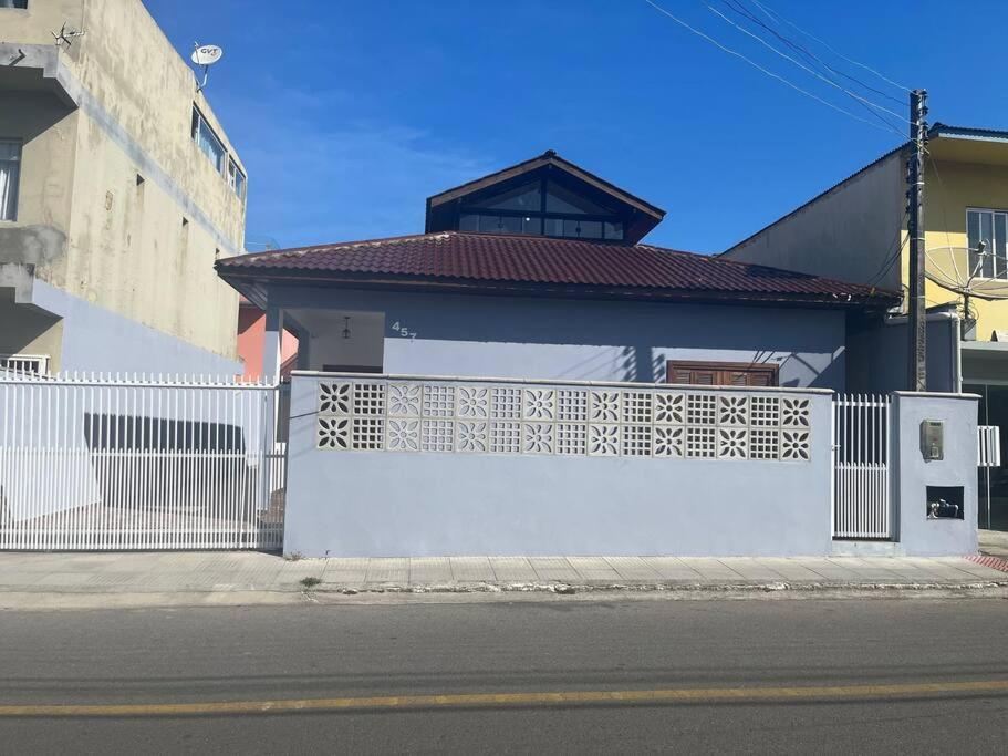 Ein weißes Gebäude mit einem Zaun an einer Straße in der Unterkunft Casa 100 metros da praia - 3 quartos in Imbituba