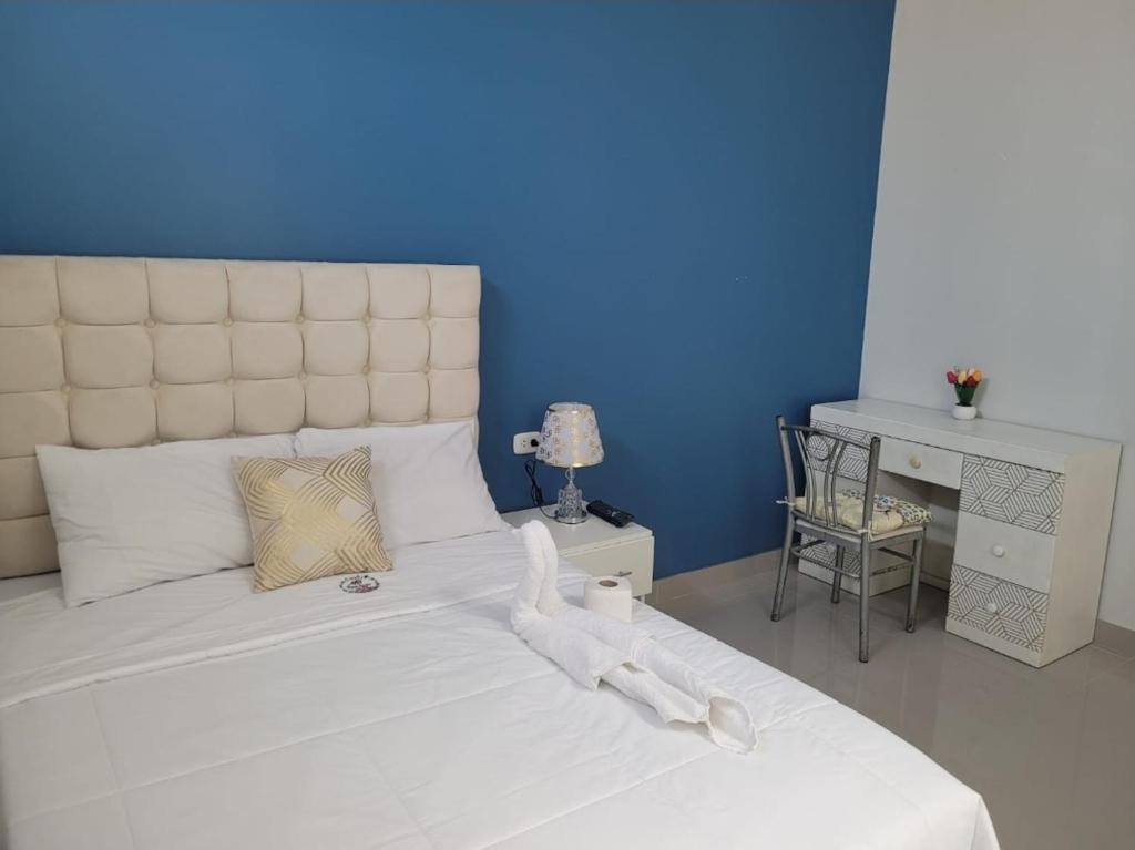 um quarto com uma grande cama branca e uma parede azul em CASA MARIA em Pisco
