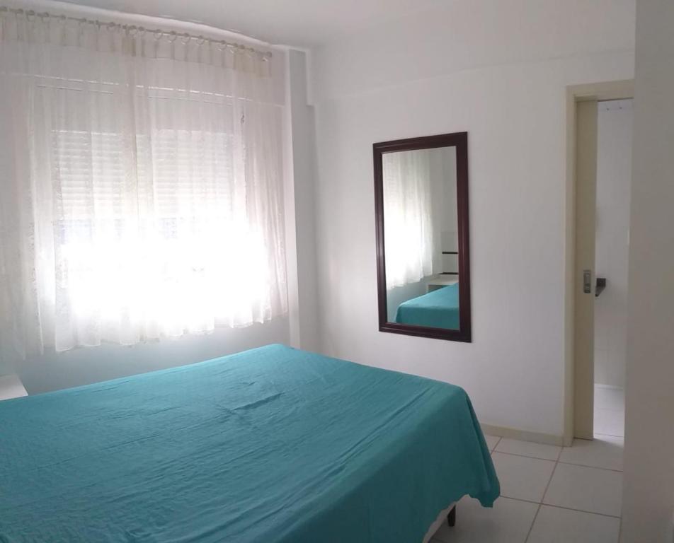 een slaapkamer met een blauw bed en een spiegel bij Pe na areia in Florianópolis