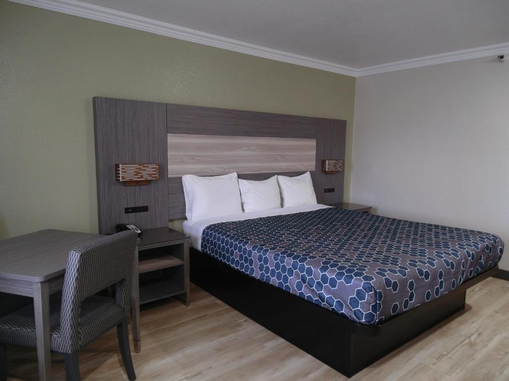 a bedroom with a bed and a table and a desk at Americas Best Value Inn-Rialto in Rialto