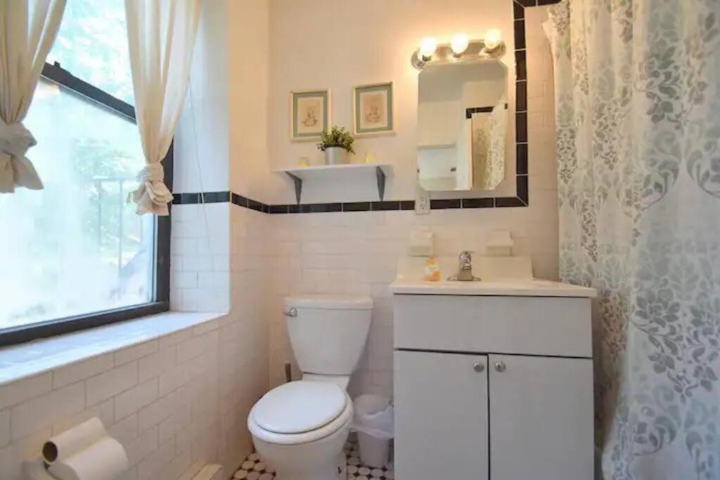 a bathroom with a toilet and a sink and a window at Lovely Full Apartment x East Village (Thompkins Square Park) in New York